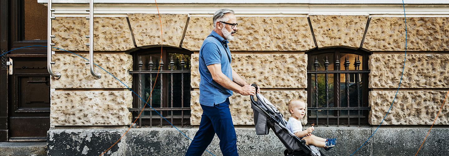 Ein Mann schiebt einen Kinderwagen durch eine Straße von Berlin. Im Hintergrund ist eine massive Hauswand aus Kalksandstein zu sehen.